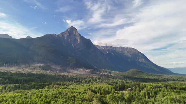 Aerial shot of a serene mountain landscape with dense forests and a clear sky at New Hazelton, showcasing vast open spaces and winding roads.