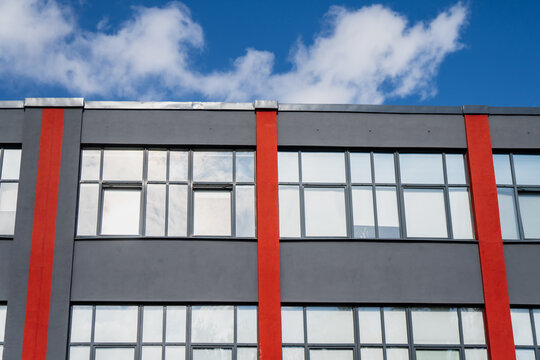 Commercial developers often use color-blocked structural elements like this, red vertical pillars dividing a grey facade into evenly spaced window bays.