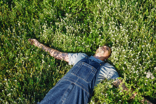Mature man relaxing in nature, lying among wildflowers, looking at sky and doing nothing