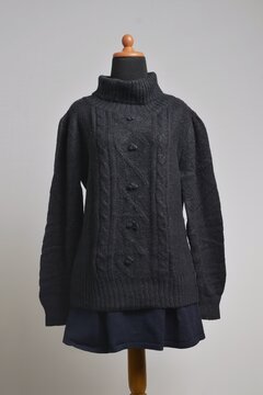 Black cable knit turtleneck sweater with mini skirt displayed on a dress form
