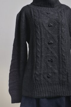 Black cable knit turtleneck sweater in details displayed on a dress form