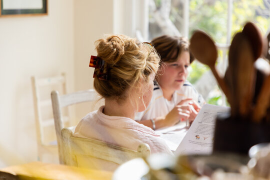 teenage boy and young woman sitting at table in light filled room