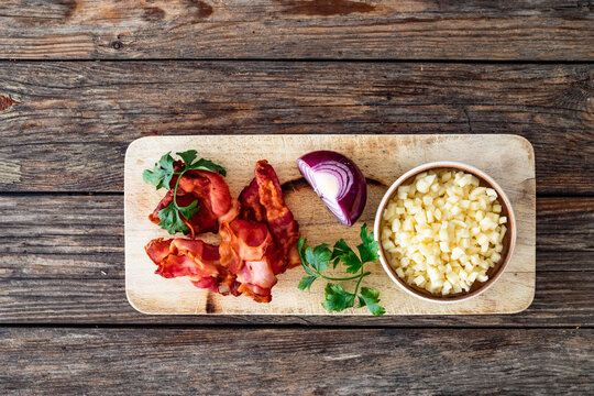 Fried bacon, mozzarella cheese, parsley and red onion on wooden background. Top view
