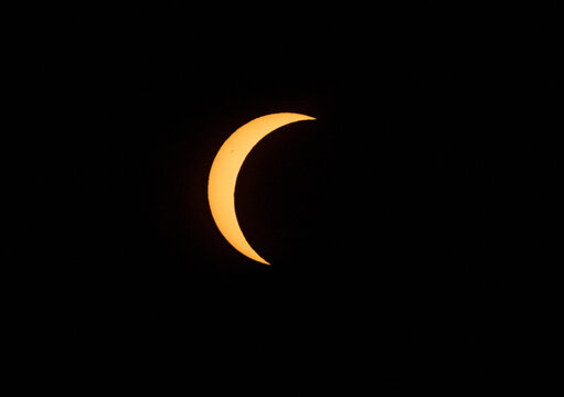 Crescent sun during a partial solar eclipse against black sky