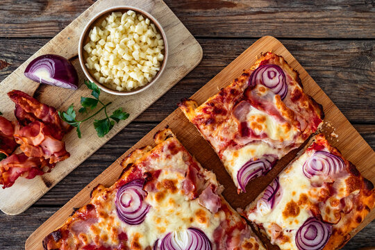Pizza with bacon, mozzarella cheese and red onion on wooden table. Top view
