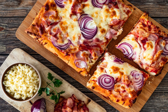 Pizza with bacon, mozzarella cheese and red onion on wooden table. Top view
