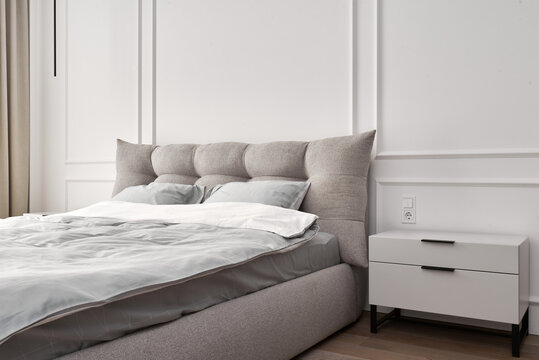 Modern Minimalist Bedroom Interior with White Bedside Table and Soft Gray Bed