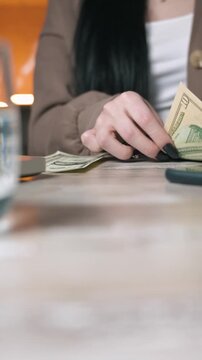 Close up woman hands counting US dollar cash on desk, budget planning vertical video thumbnail