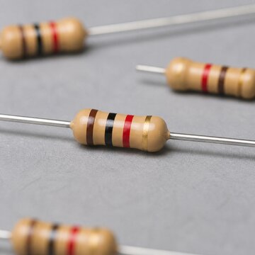 Close-up of brown resistors with color-coded bands on a gray background