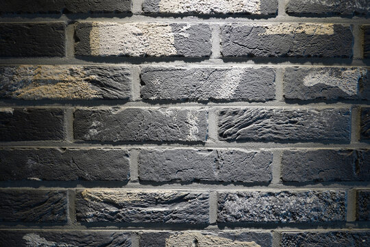 Dark grey brick wall texture background with overhead spotlight effect
