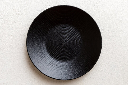 Top view of black plate on cement background. Empty space for your design