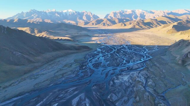 An aerial view of the typical landscape in the Kok Kiya Valley in Kyrgyzstan. Green valleys with pastures for horses, sheep and cows, and the high mountains with the Tian Shan glaciers. Summer holiday