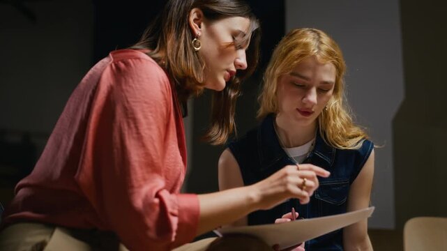 Caucasian young adult women reading script together during acting rehearsal, low angle shot. Ideal for arts education, drama school advertising, student collaboration campaigns