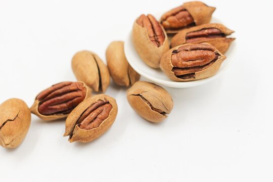 Group of whole and cracked pecan nuts with kernels, isolated on a clean white background.