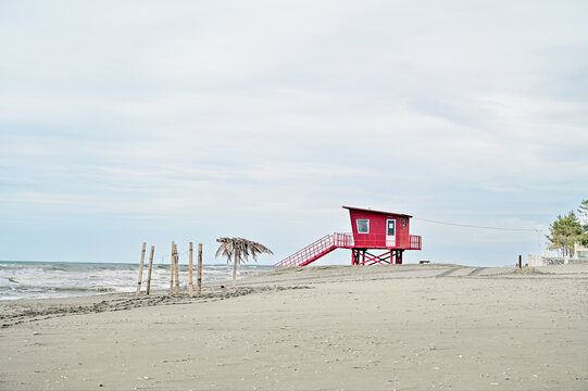 Red lifeguard tower on a quiet sandy Black Sea beach under an overcast sky, on the coast of Poti, Samegrelo-Zemo Svaneti region, Georgia.
