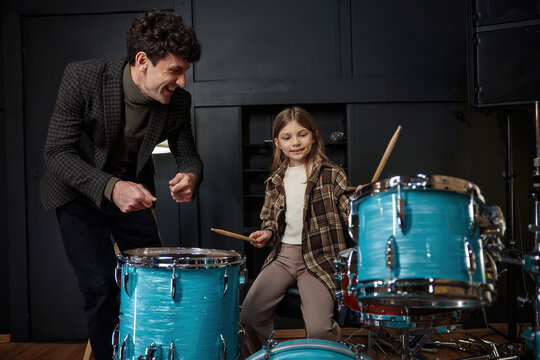 Mentor guides young girl through her drumming lesson in inviting studio setting