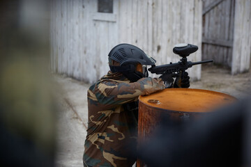 Obraz premium A soldier aims a gun while leaning on a drum, hiding behind