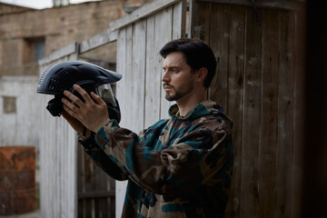 Obraz premium A man soldier is looking at his defensive helmet at the battlefield