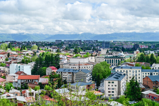 Panoramic view of the Old Town of Kutaisi with its traditional houses, church towers, and green hills under a partly cloudy sky, Imereti region, Georgia