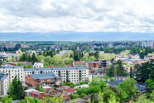 Panoramic view of the Old Town of Kutaisi with its traditional houses, church towers, and green hills under a partly cloudy sky, Imereti region, Georgia