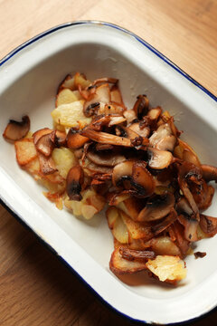 Pan-fried potatoes with wild mushrooms in enamel dish close up