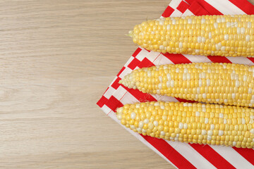 Fototapeta premium Fresh corn on the cob on a colorful background, top view 