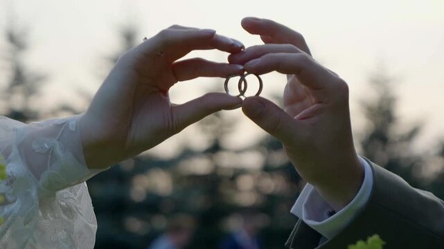Close-up of a newlywed couple gently holding their wedding bands together, creating a romantic symbol of love and commitment during the wedding day.
