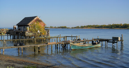 Sf. Gheorghe, Romania - April 25, 2025: Wooden fishery, pontoon and boat on river bank of Danube Delta © MEDIAIMAG