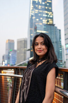 Young indonesian woman smiling on modern city bridge