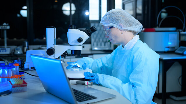 Female Scientist Working with Microscope and Laptop in Modern Research Laboratory