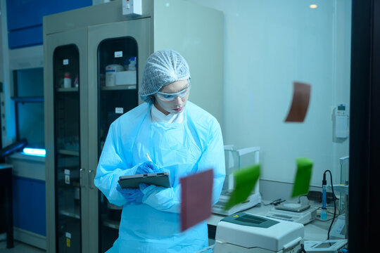 Female Scientist in Protective Gear Using Tablet in Modern Laboratory Clean Room Environment