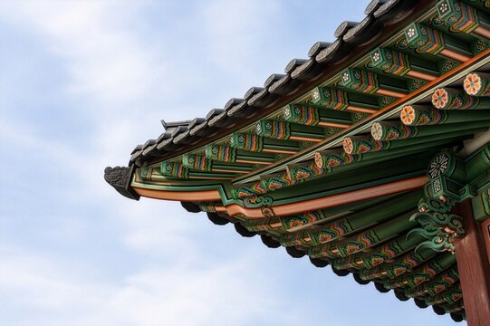 Colorful dancheong patterns on traditional Korean temple eaves against blue sky