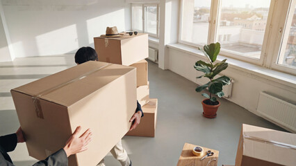 Fototapeta premium People carrying large cardboard boxes moving into new house or apartment interior design project.