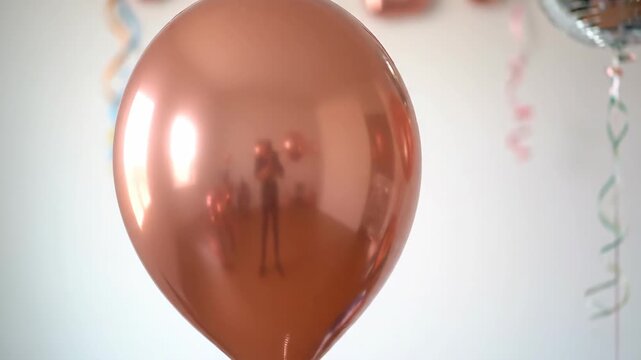 Shiny metallic balloon with reflection of people at a festive party. Perfect for birthday, wedding, and celebration concepts