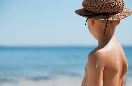 Child by the sea at summer vacation with sun protectin sunscreen and hat