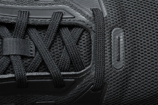 Black athletic running shoe close up with detailed laces, breathable mesh fabric and modern sole construction, monochrome sports footwear background for fitness, training, lifestyle and fashion concep