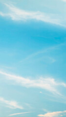 Obraz premium Vertical view of a soft blurred bright blue sky filled with wispy white clouds creating a calm peaceful and dreamy natural background