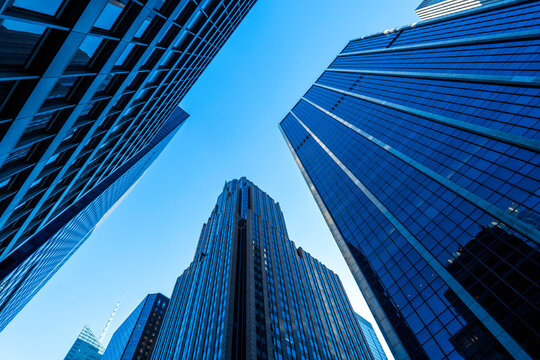 Modern skyscrapers and glass office buildings in business district, captured from low angle perspective with blue sky, symbolizing architecture, urban growth, corporate success, and city development.