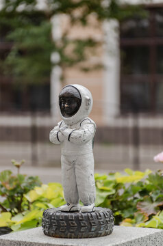 Kaluga, kaluga region, russia - august 27, 2026: Miniature bronze cosmonaut tester sculpture in white space suit standing on car tire.