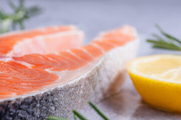 Close-up salmon fillet sits on ice surrounded by lemon slices and rosemary sprigs, the focus is shifted to the fish scales. Healthy nutrition and fish market presentation. side view © HalynaRom