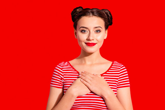 Close up photo beautiful amazing she her lady pretty hairdo two buns red pomade lips hold hands arms on heart eyes closed overjoyed wear casual striped red white t-shirt isolated pink background