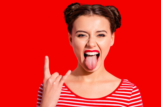 Close up photo beautiful carefree she her lady pretty hairdo two buns bright red pomade big lips tongue out mouth rocker gesture wear casual striped red white t-shirt isolated pink background