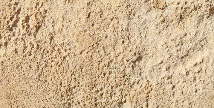 Rough cracked beige sandstone wall surface texture background with deep natural erosion