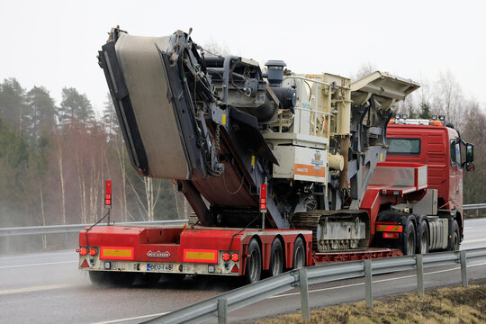 Red Volvo FH 520 semi-truck hauls Metso Lokotrack LT1110 Impactor plant on the highway as oversize load, rear view. 