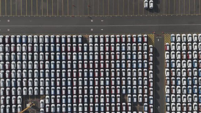 Hundreds of new vehicles arranged in rows at Port of Veracruz terminal, aerial top-down overhead textured backdrop of supply chain linkage