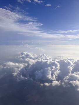 Aerial view of dramatic fluffy white cumulus clouds under deep blue sky