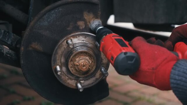 Cleaning brake caliper mounting surfaces on wheel hub with rotary wire brush. Rust removal preparing hub contact points for caliper bracket installation. DIY automotive maintenance restoring clean