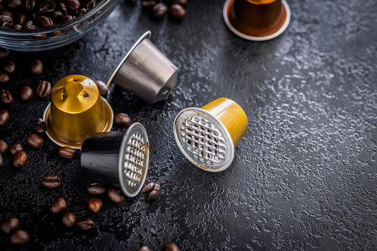 Used Coffee Capsules and Roasted Beans on Dark Textured Surface for Espresso Brewing