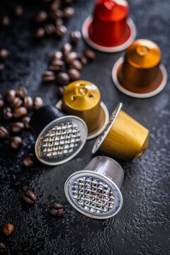 Used Coffee Capsules and Roasted Beans on Dark Textured Surface for Espresso Brewing