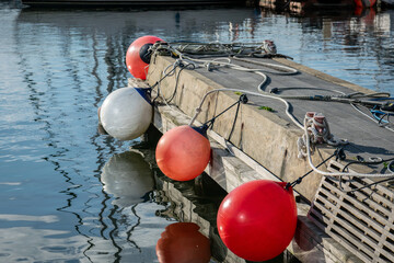 Wooden dock with mooring buoys reflected in calm harbor water © Vladimir Arndt